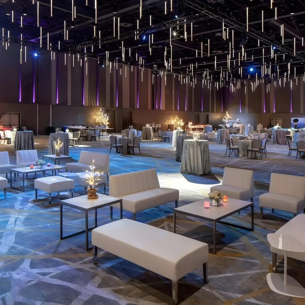 A large, modern event space with lounge seating, cocktail tables, and dramatic overhead lighting.