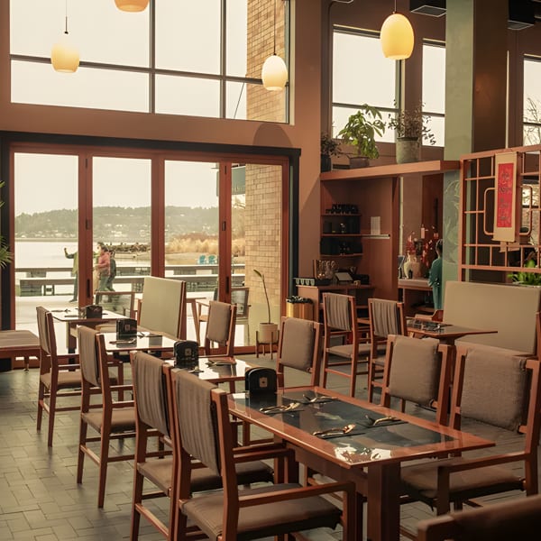 Spacious restaurant dining room with wooden tables and chairs, large windows overlooking a lake.
