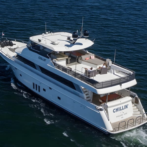 Aerial view of a large white yacht named "Chillin'" cruising on deep blue water.