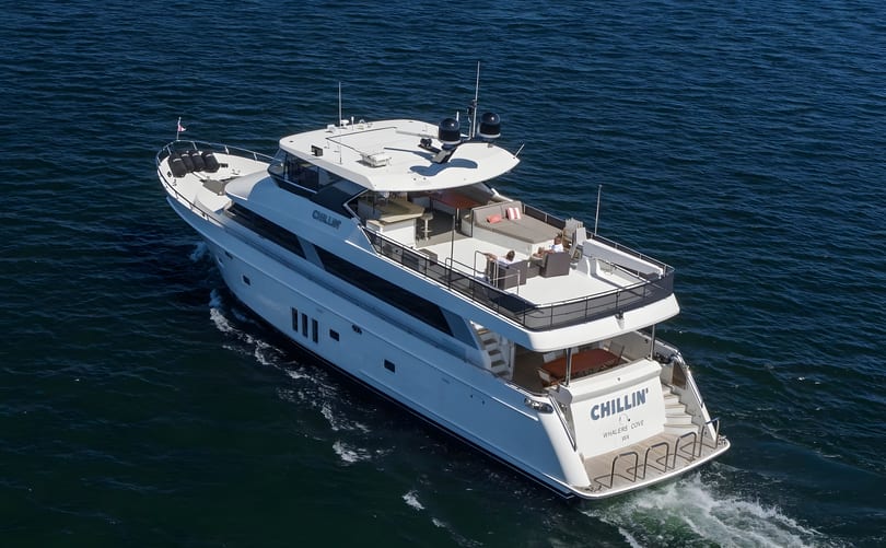 Aerial view of a large white yacht named "Chillin'" cruising on deep blue water.