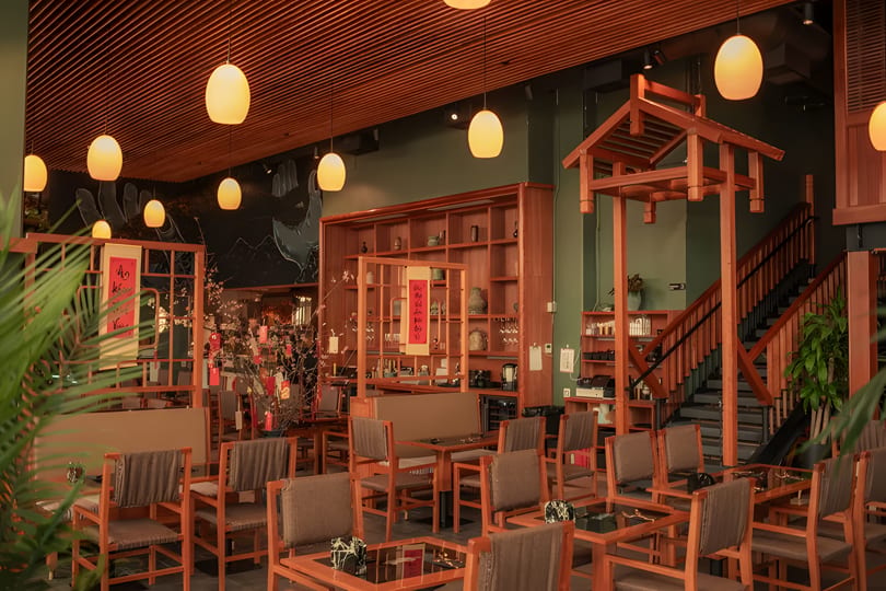 A restaurant interior with wooden furniture, warm lighting, and traditional Asian decor.