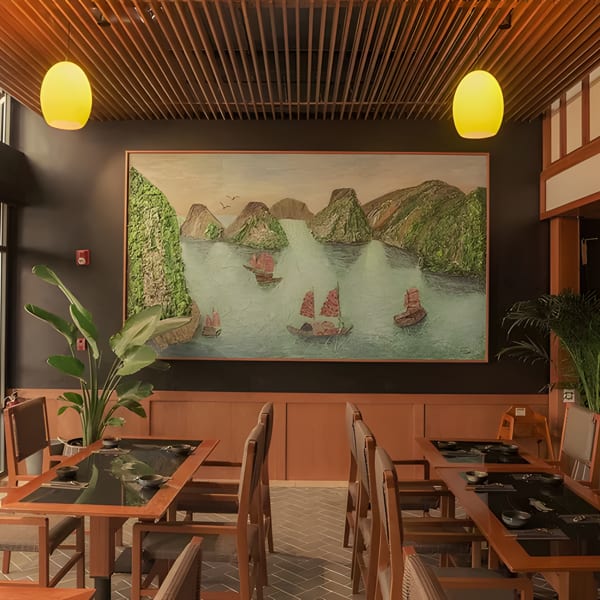 Restaurant interior with dark walls, wooden tables, chairs, and a large painting of boats on water.