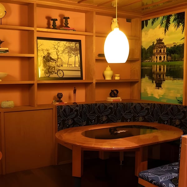 A cozy restaurant booth with a wooden table, shelves, and large scenic wall art.