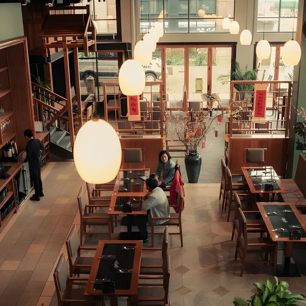 Overhead view of a restaurant dining room with wooden tables, chairs, and glowing pendant lights.