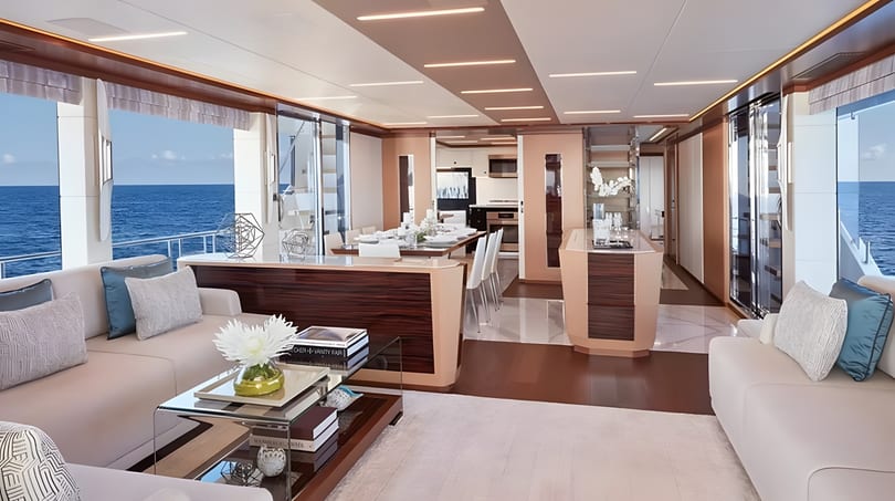 Luxurious yacht interior with a living area, dining table, and ocean views through large windows.
